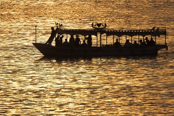 Silhouette of water taxi with tourists on the river Nile at sunset