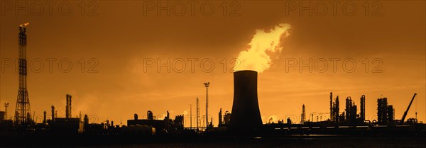 Industrial estate showing cooling tower silhouetted against sunset at the BASF chemical production site in the port of Antwerp