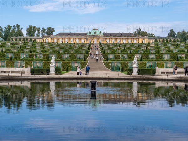 The water reflection of the Great Fountain and behind it Sanssouci Palace with the staircase and Sanssouci Park