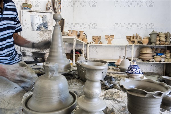 Skillful potter forming a vessel out of gray clay in a pottery factory