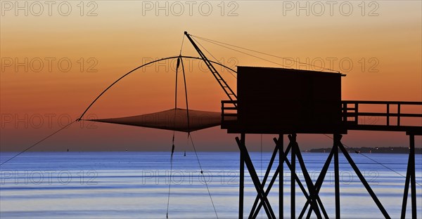 Traditional carrelet fishing hut with lift net on the beach at sunset