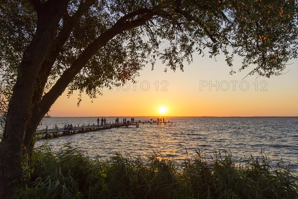 Tourists watching sunset from jetty at Lake Steinhude