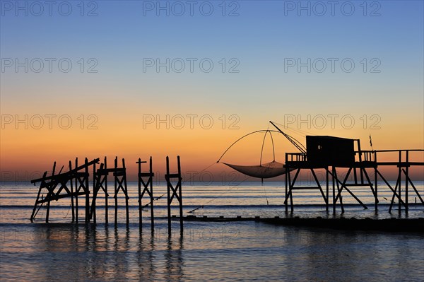 Traditional carrelet fishing hut with lift net on the beach at sunset