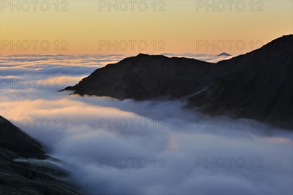 View over mountains covered in mist at sunrise seen from the Col du Tourmalet