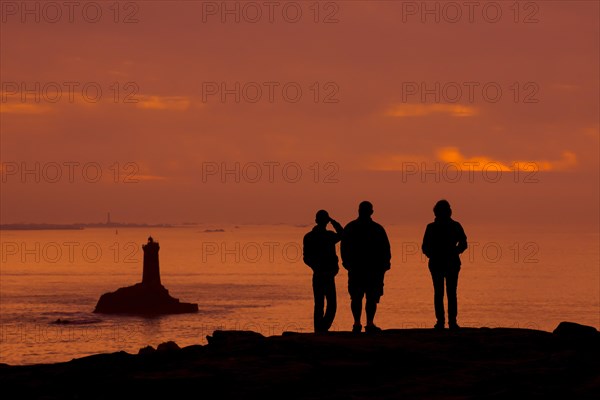 Tourists watching the lighthouse La Vieille in the strait Raz de Sein silhouetted against sunset at the Pointe du Raz