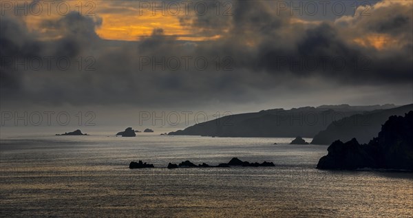 Sea cliffs at the Pointe de Penharn at sunrise with storm clouds