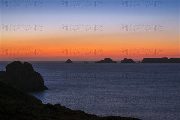 Sea cliffs at the Pointe de Pen-Hir and Les Tas de Pois sea stacks silhouetted against sunset on the Crozon Peninsula
