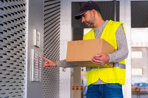 A young delivery man in a protective uniform delivering the online order in a home ringing the doorbell