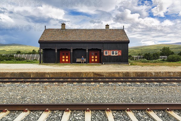 Man sitting lonely on a bench looking at the tracks