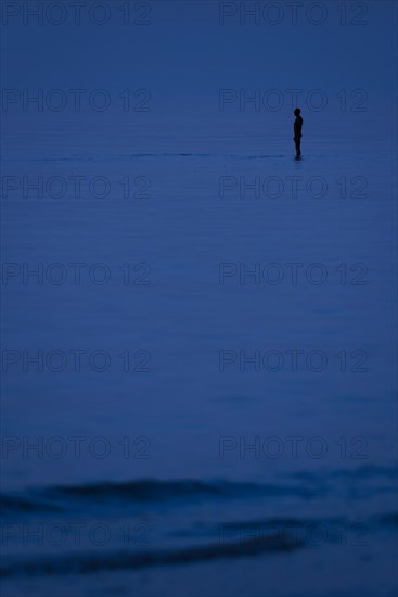 Sculpture Another Time XVI by Antony Gormley silhouetted at night along the North Sea coast at Knokke-Heist