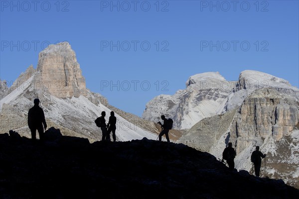 Mountain walkers silhouetted against Torre dei Scarperi