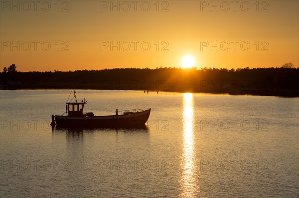 Fishing boat silhouetted against sunset