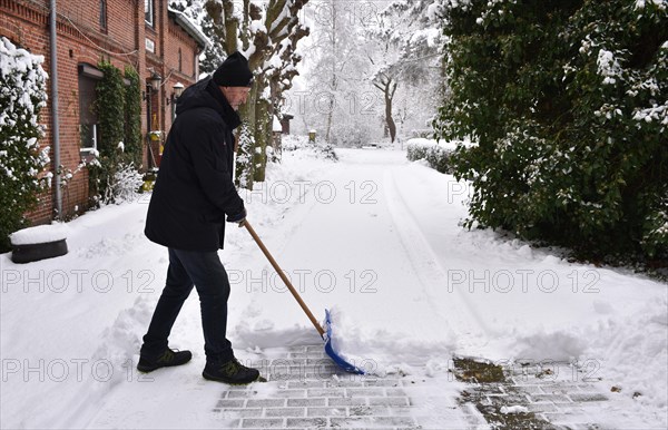 Man pushing snow on pavement