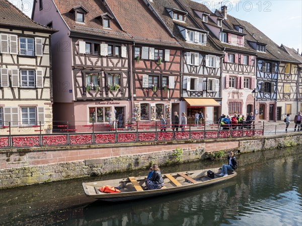 Half-timbered houses along the course of the Lauch with boat and tourists in the district of La Petite Venise