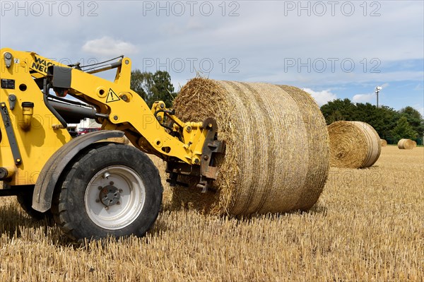 Round bales are loaded with a wheel loader