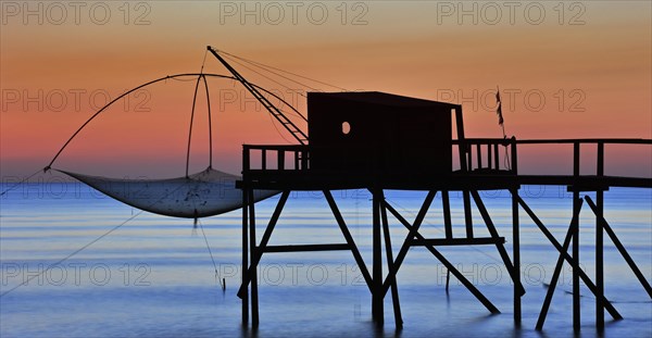 Traditional carrelet fishing hut with lift net on the beach at sunset