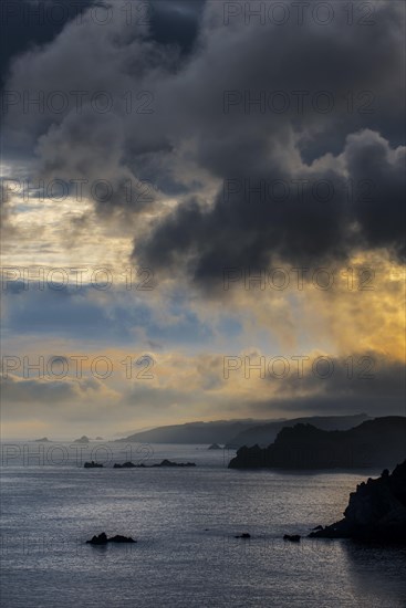 Sea cliffs at the Pointe de Penharn at sunrise with storm clouds
