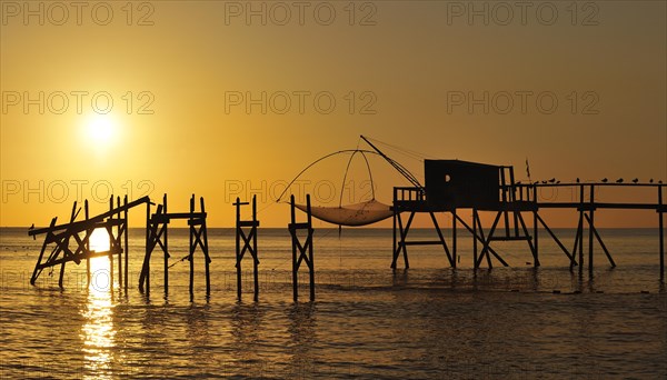 Traditional carrelet fishing hut with lift net on the beach at sunset