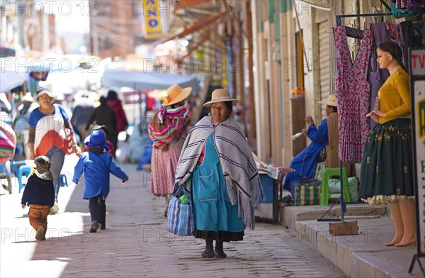 Aymara woman in traditional dress walks through a shopping street in Copacabana