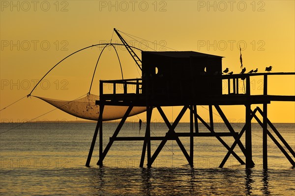 Traditional carrelet fishing hut with lift net on the beach at sunset