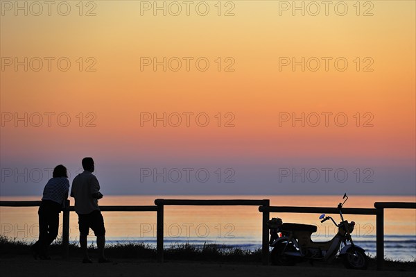 Couple looking at sunset at Saint-Denis-d'Oleron on the island Ile d'Oleron