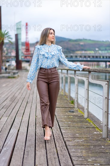 Young woman walking along the river in the city