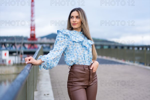 Portrait young woman on a city river bridge