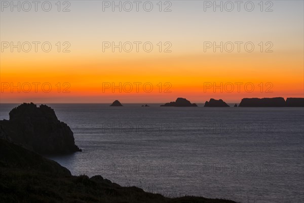 Sea cliffs at the Pointe de Pen-Hir and Les Tas de Pois sea stacks silhouetted against sunset on the Crozon Peninsula