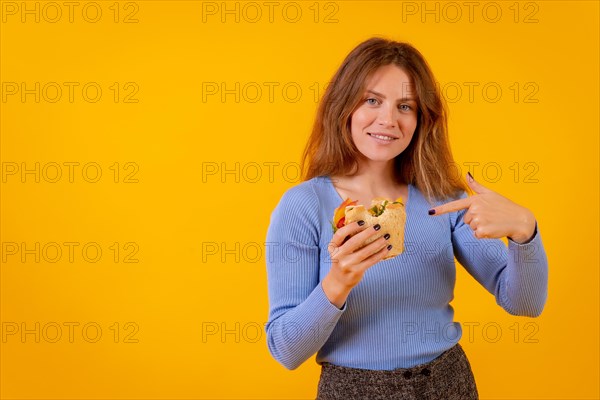 Woman pointing at a vegetarian sandwich on a yellow background