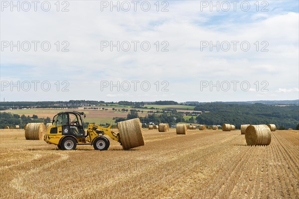 Round bales are loaded with a wheel loader