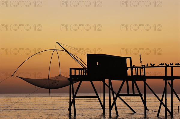 Traditional carrelet fishing hut with lift net on the beach at sunset