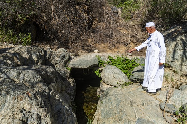 Old man pointing on a mountain spring