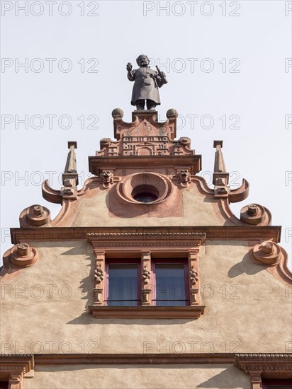 The top of a medieval building La Maison des Tetes with a male statue at the top of Rue des Tetes