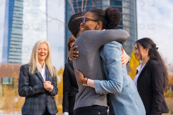 Middle-aged multi-ethnic businessmen and businesswomen giving each other a hug between colleagues