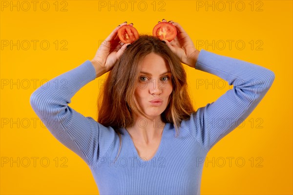 Vegan woman with tomato slices on her head on a yellow background