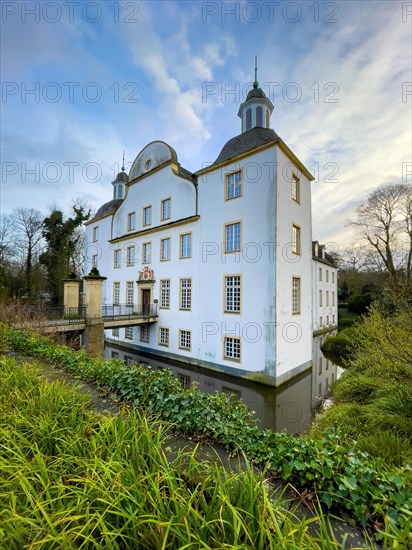 View over moat to front entrance corner tower of historic moated castle Burg Schloss Borbeck in winter