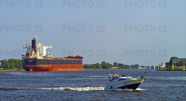 Bulk Carrier YM Endeavour and a pleasure boat on the Weser near Bremen Vegesack