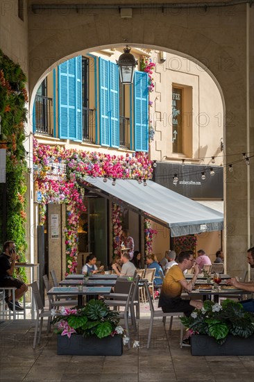 Archway and restaurant with floral decorations at Placa Major