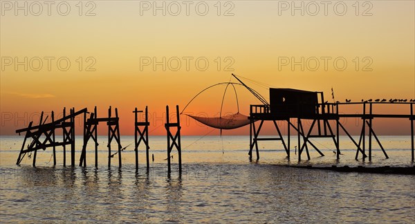 Traditional carrelet fishing hut with lift net on the beach at sunset