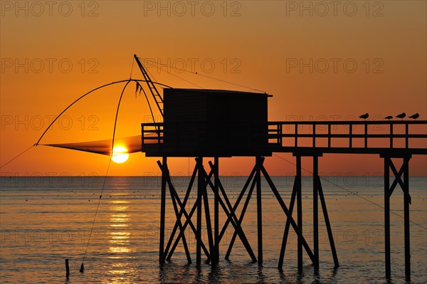 Traditional carrelet fishing hut with lift net on the beach at sunset