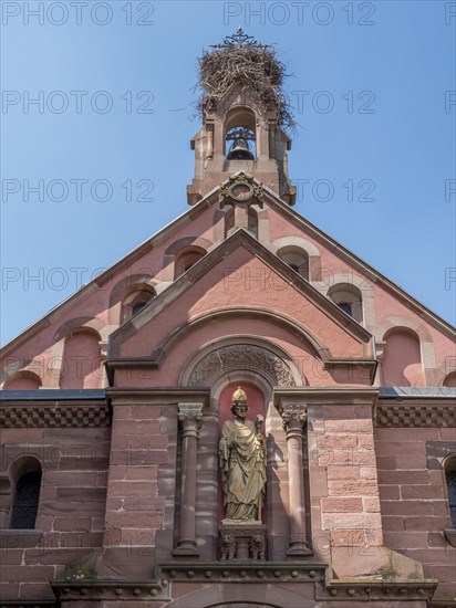 The roof section of the neo-Romanesque Byzantine St. Leo Chapel with a stork's nest on the bell tower and a sculpture on the wall