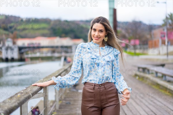 Portrait of young woman walking along the river in the city