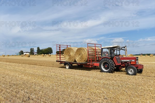 Round bales are loaded onto tractor and trailer with wheel loader