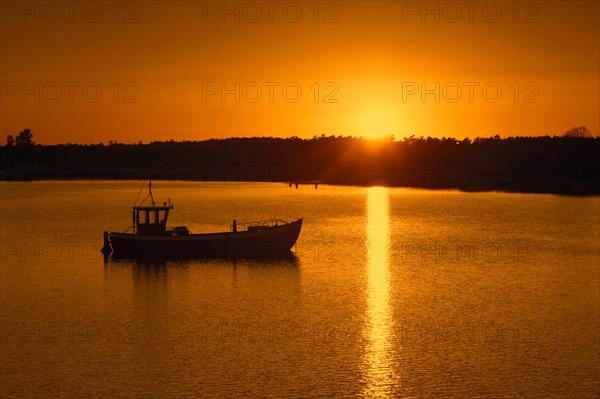 Fishing boat silhouetted against sunset