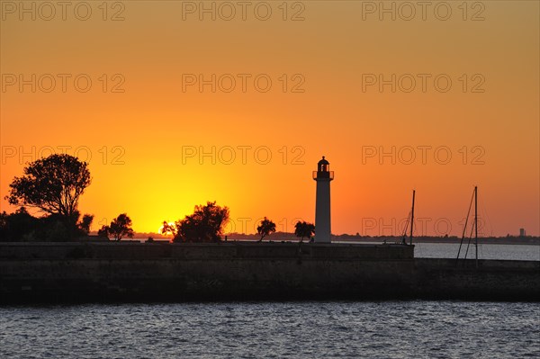 Silhouette of lighthouse at sunset in the harbour at Saint-Martin-de-Re on the island Ile de Re