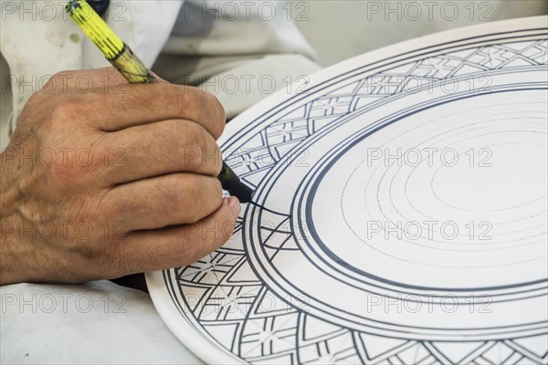 Craftsman painting and decorating ceramic products in pottery factory in Fez