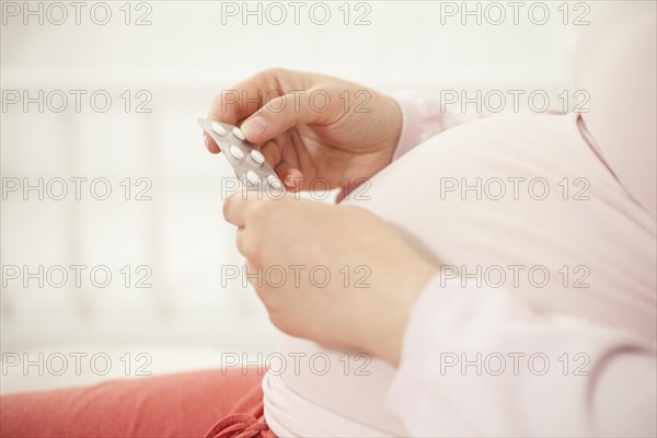 Pregnant woman holding pills | MR:yes NH_pregnant_belly_mr