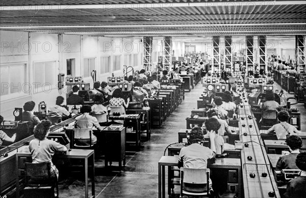 Old black and white archival photograph showing female workers manufacturing small electric motors in factory in the 1950s