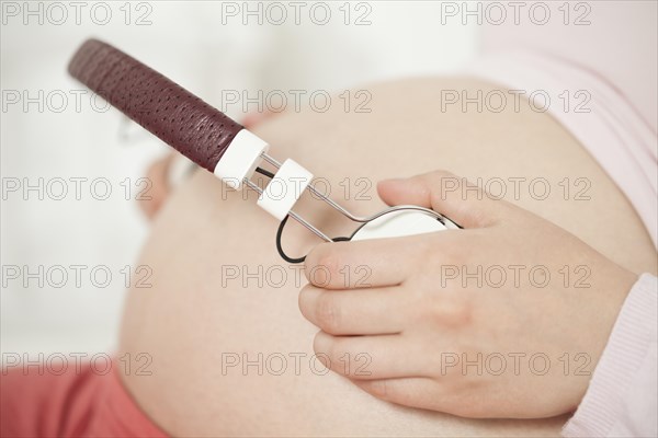 Pregnant woman with headphones on baby belly | MR:yes NH_pregnant_belly_mr