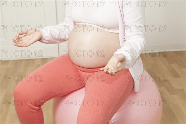 Pregnant woman sitting on an exercise ball and meditating